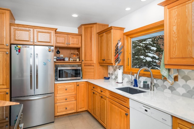 kitchen with appliances with stainless steel finishes, sink, backsplash, light tile patterned floors, and light stone counters