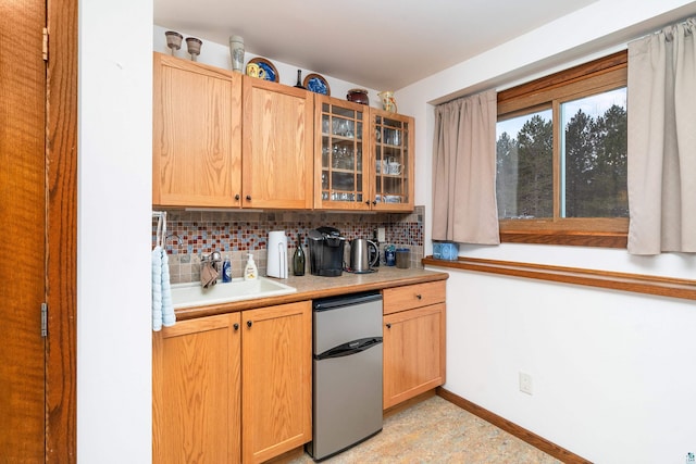 kitchen with tasteful backsplash, sink, and stainless steel refrigerator