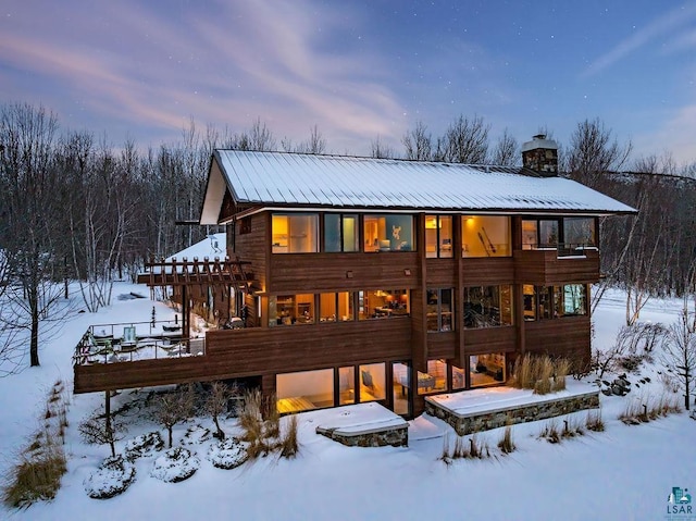 snow covered rear of property featuring a balcony