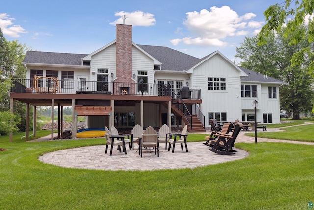 rear view of house featuring a wooden deck, a patio area, and a lawn
