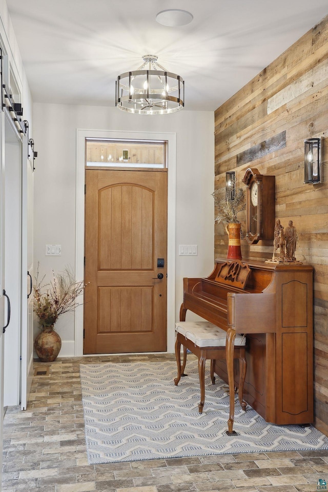 entryway featuring an inviting chandelier, wooden walls, and a barn door