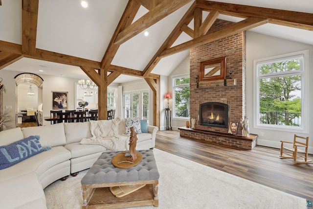 living room with high vaulted ceiling, a fireplace, hardwood / wood-style flooring, a notable chandelier, and beam ceiling