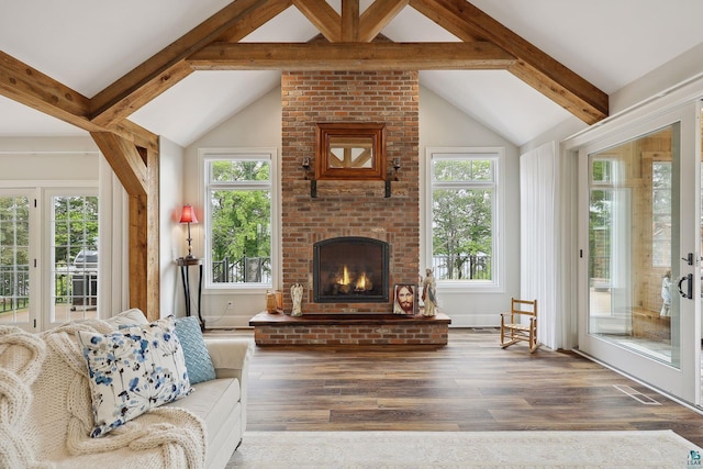 living room with a brick fireplace, vaulted ceiling with beams, hardwood / wood-style floors, and plenty of natural light