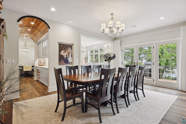 dining space with hardwood / wood-style floors, a chandelier, and french doors