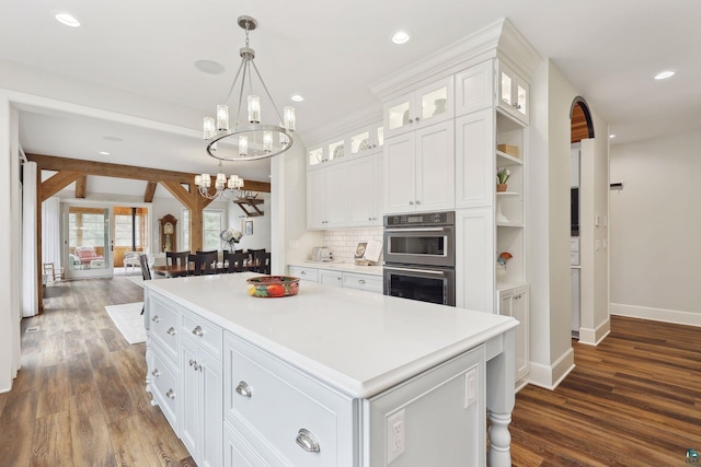 kitchen with white cabinetry, an inviting chandelier, hanging light fixtures, a kitchen island, and stainless steel double oven
