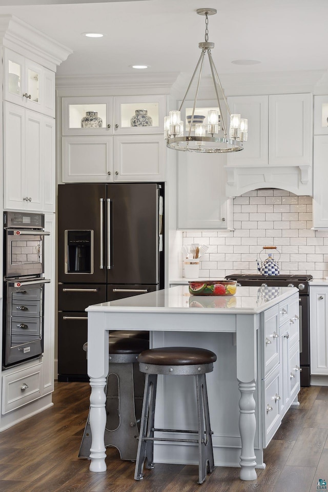 kitchen with black range, high end refrigerator, white cabinets, and a kitchen island