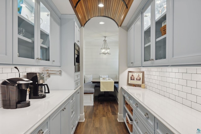 bar featuring hanging light fixtures, backsplash, and dark hardwood / wood-style flooring