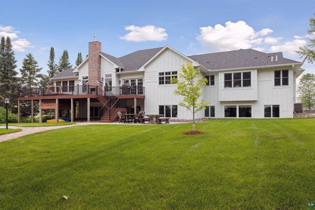 rear view of house featuring a wooden deck, a patio, and a lawn