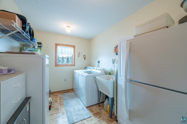 washroom featuring independent washer and dryer, a textured ceiling, and light tile patterned flooring