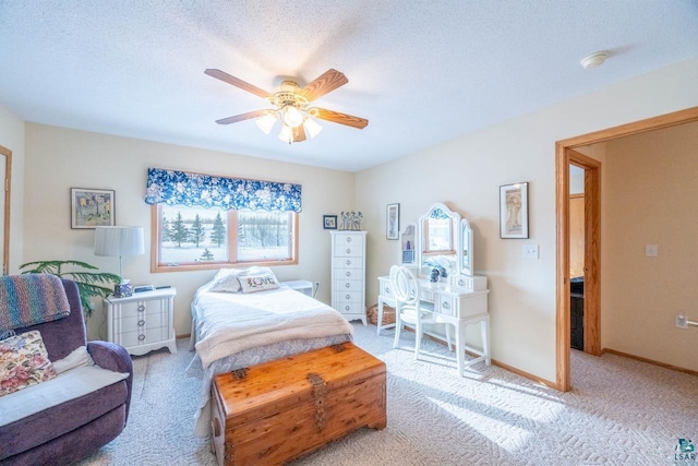 bedroom with ceiling fan, light colored carpet, and a textured ceiling