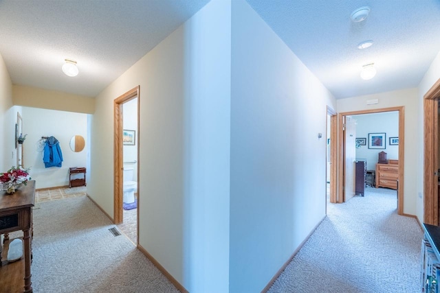 hall featuring light colored carpet and a textured ceiling