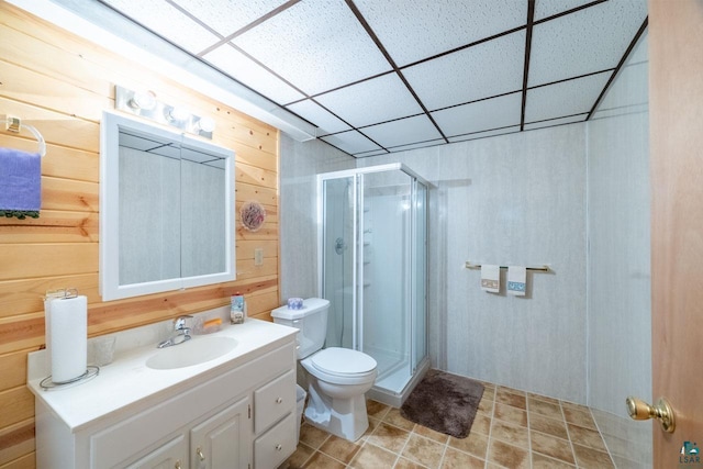 bathroom featuring vanity, a shower with door, toilet, and wood walls