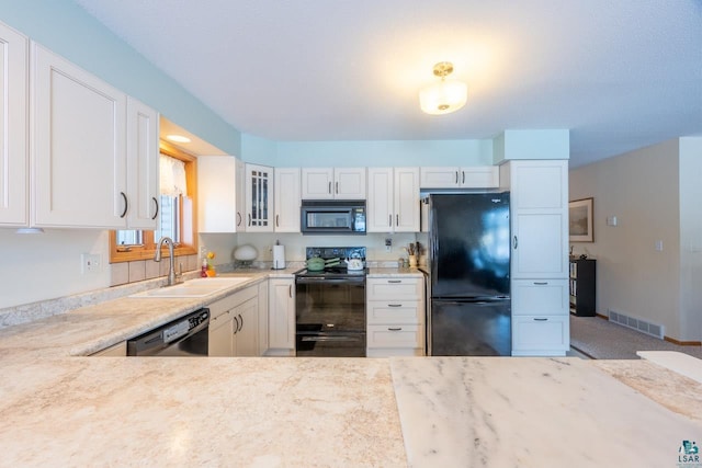 kitchen featuring white cabinetry, sink, light stone counters, and black appliances