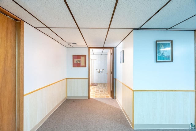 corridor featuring light colored carpet and a drop ceiling