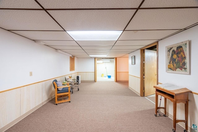 living area with a paneled ceiling and light carpet