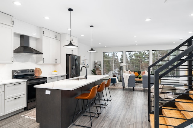 kitchen featuring stainless steel fridge, a breakfast bar area, electric range, and wall chimney exhaust hood