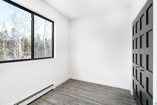 spare room featuring a baseboard radiator, plenty of natural light, and wood-type flooring