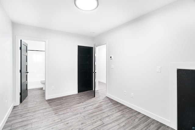 unfurnished bedroom featuring connected bathroom and light hardwood / wood-style floors