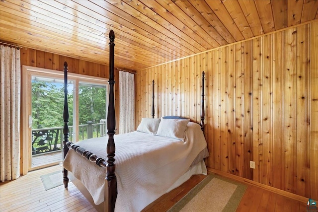 bedroom featuring access to exterior, hardwood / wood-style floors, and wood walls