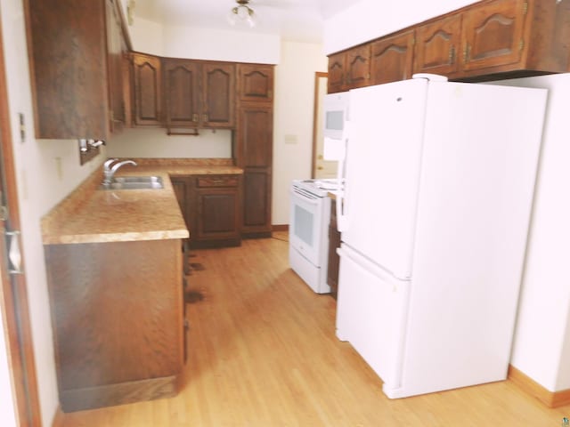 kitchen featuring sink, white appliances, and light hardwood / wood-style floors