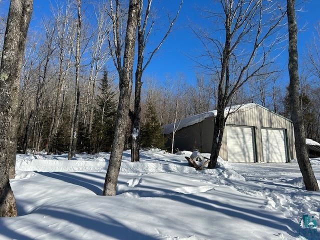 snowy yard with a garage and an outdoor structure