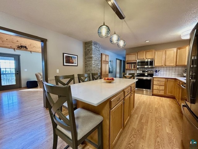 kitchen featuring pendant lighting, a breakfast bar, stainless steel appliances, a center island, and decorative backsplash