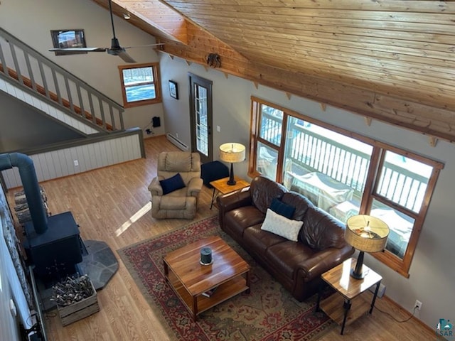 living room with vaulted ceiling, a baseboard radiator, a wood stove, light hardwood / wood-style floors, and wooden ceiling