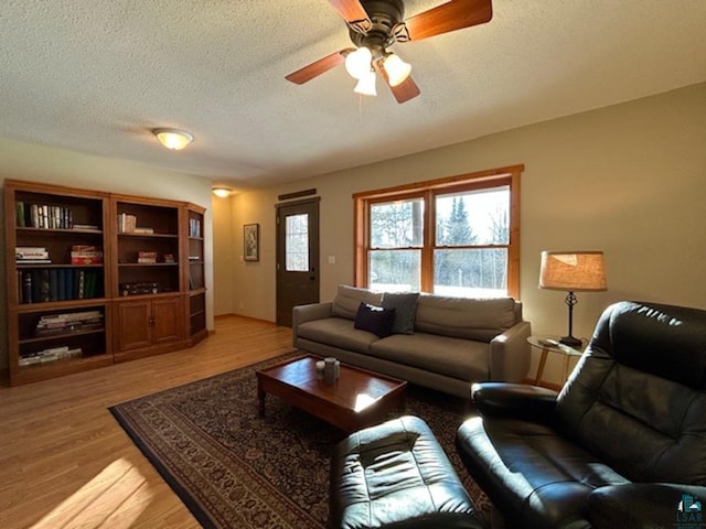 living room featuring ceiling fan, a textured ceiling, and light hardwood / wood-style flooring