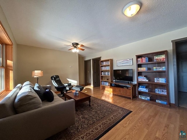 living room with ceiling fan, wood-type flooring, and a textured ceiling