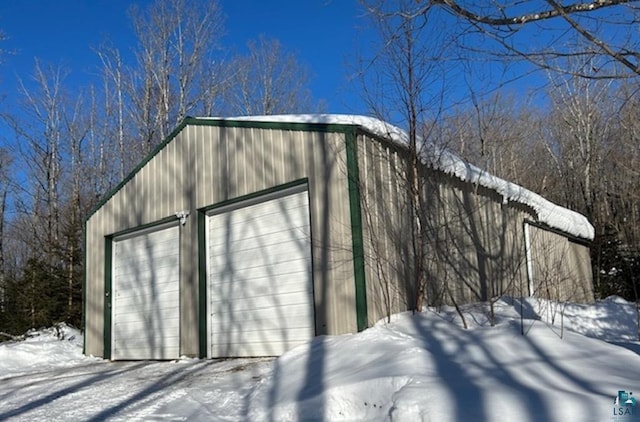 snow covered structure with a garage