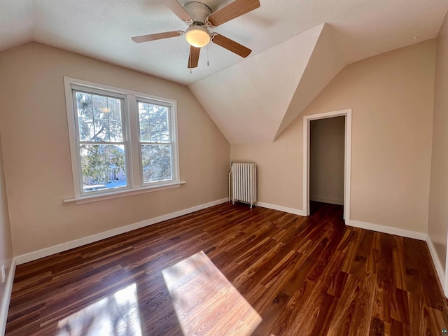 additional living space with ceiling fan, lofted ceiling, dark wood-type flooring, and radiator