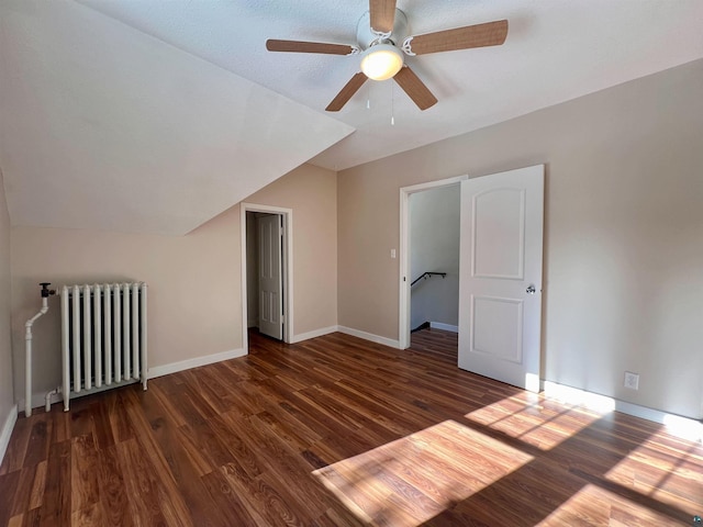 additional living space with dark wood-type flooring, vaulted ceiling, radiator heating unit, and ceiling fan