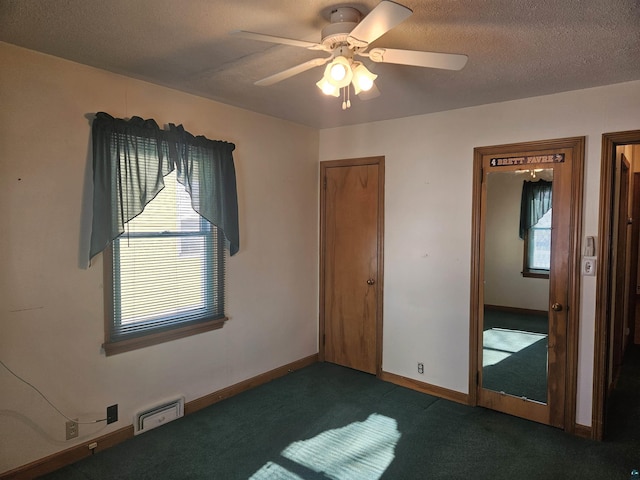 unfurnished bedroom featuring a textured ceiling, dark carpet, and ceiling fan