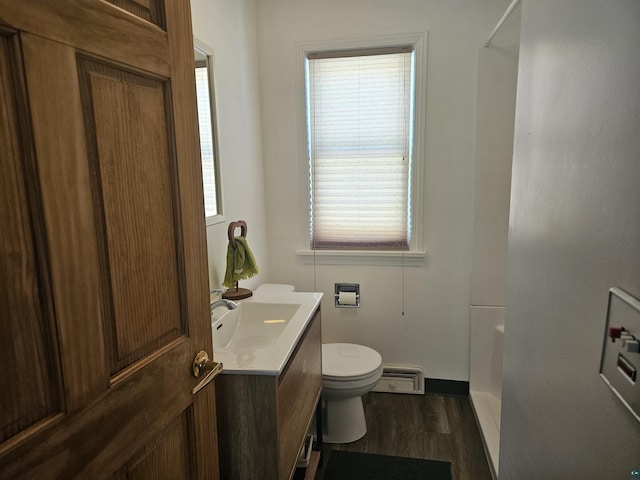 bathroom with wood-type flooring, vanity, walk in shower, toilet, and a baseboard radiator