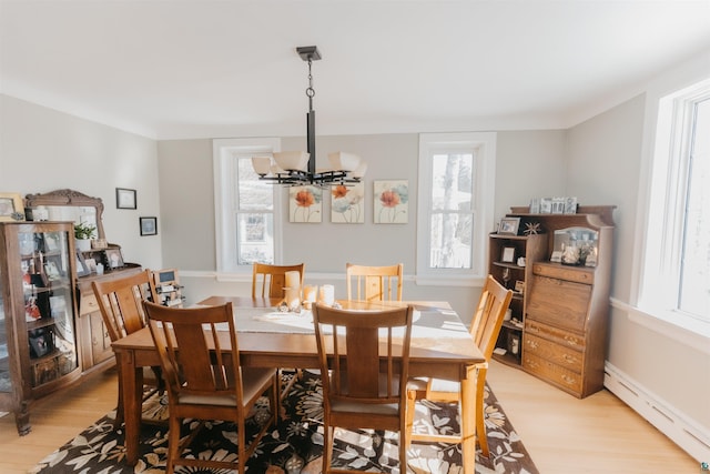 dining space with a baseboard radiator, an inviting chandelier, and light hardwood / wood-style floors