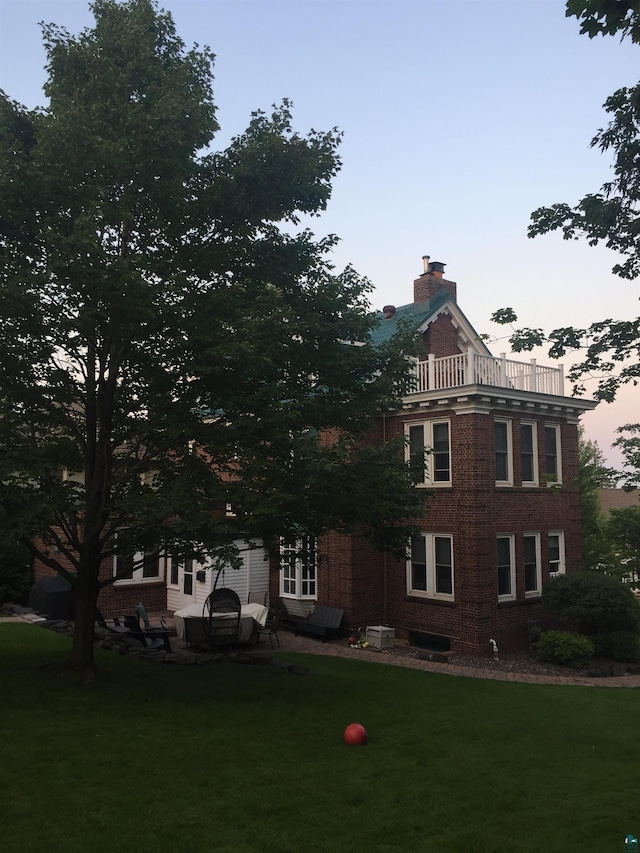 exterior space featuring central AC unit, a balcony, and a lawn