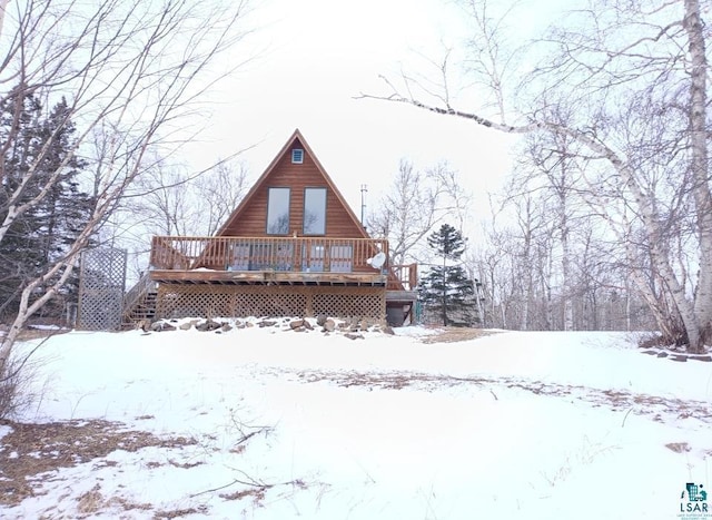 snow covered back of property with a deck