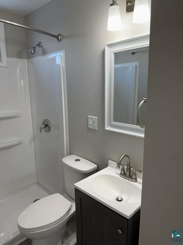 bathroom featuring vanity, toilet, and a shower