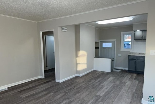 unfurnished living room with dark wood-type flooring, ornamental molding, baseboards, and a textured ceiling