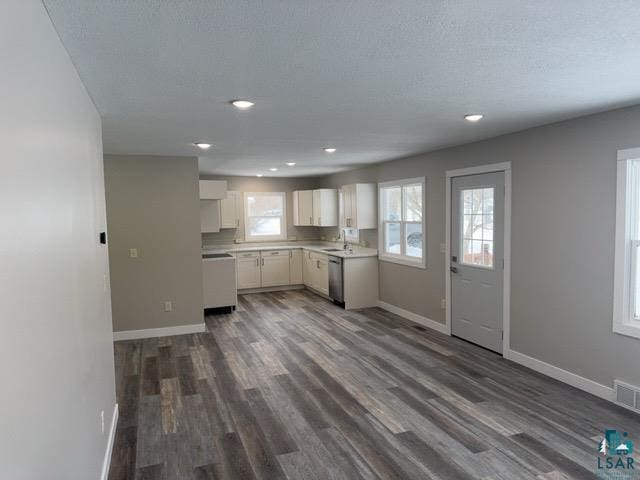 kitchen with dark hardwood / wood-style flooring, stainless steel dishwasher, a textured ceiling, and white cabinets