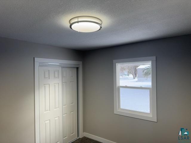 unfurnished bedroom featuring carpet, a textured ceiling, and a closet