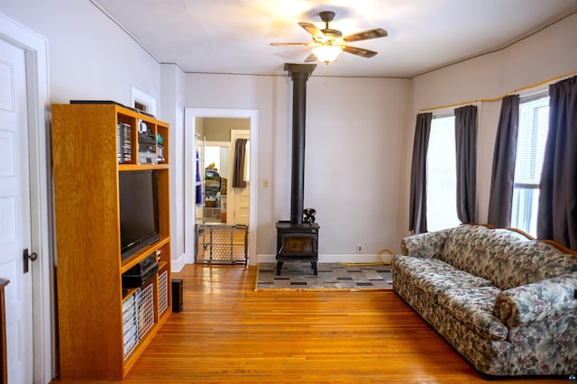 living room featuring ceiling fan, a wood stove, and wood-type flooring