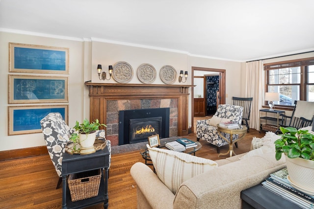 living area with a fireplace, baseboards, wood finished floors, and crown molding