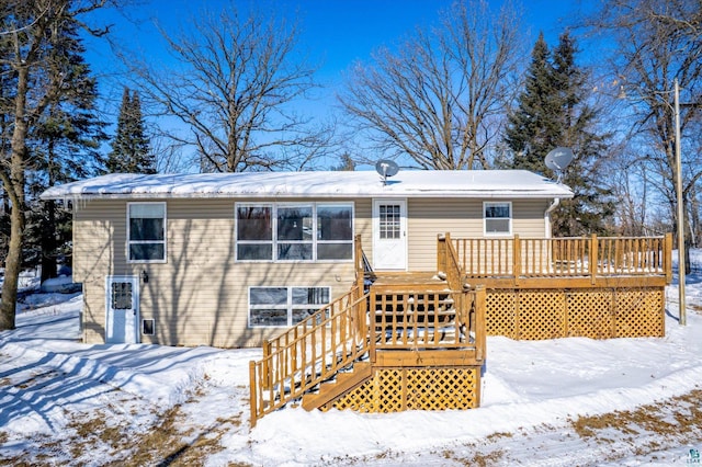 snow covered back of property featuring a deck