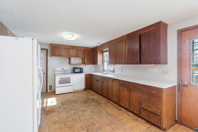 kitchen featuring light countertops, brown cabinetry, a sink, a textured ceiling, and white appliances