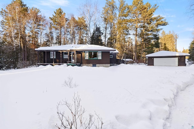 view of front of property with a detached garage, a porch, and an outbuilding