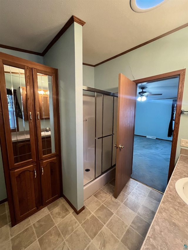 full bath with a textured ceiling, vanity, baseboards, a stall shower, and crown molding