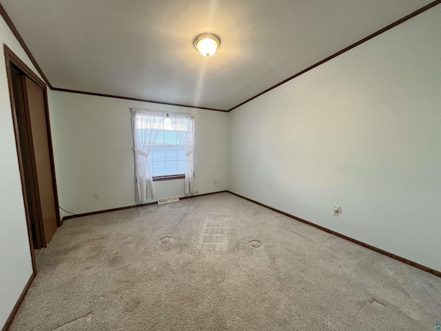 unfurnished bedroom featuring baseboards, visible vents, crown molding, and carpet flooring