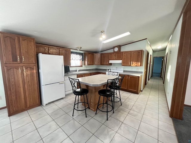 kitchen with white appliances, a kitchen island, a breakfast bar, and light tile patterned flooring