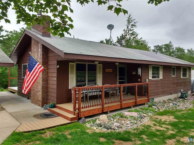 view of front of home featuring covered porch, a shingled roof, and a chimney